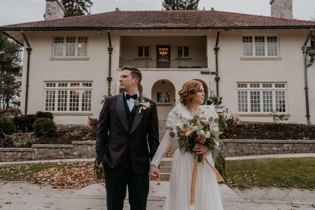 Bride and Groom holding hands with bouquet in front of Elsie Perrin Williams Estate wedding venue.